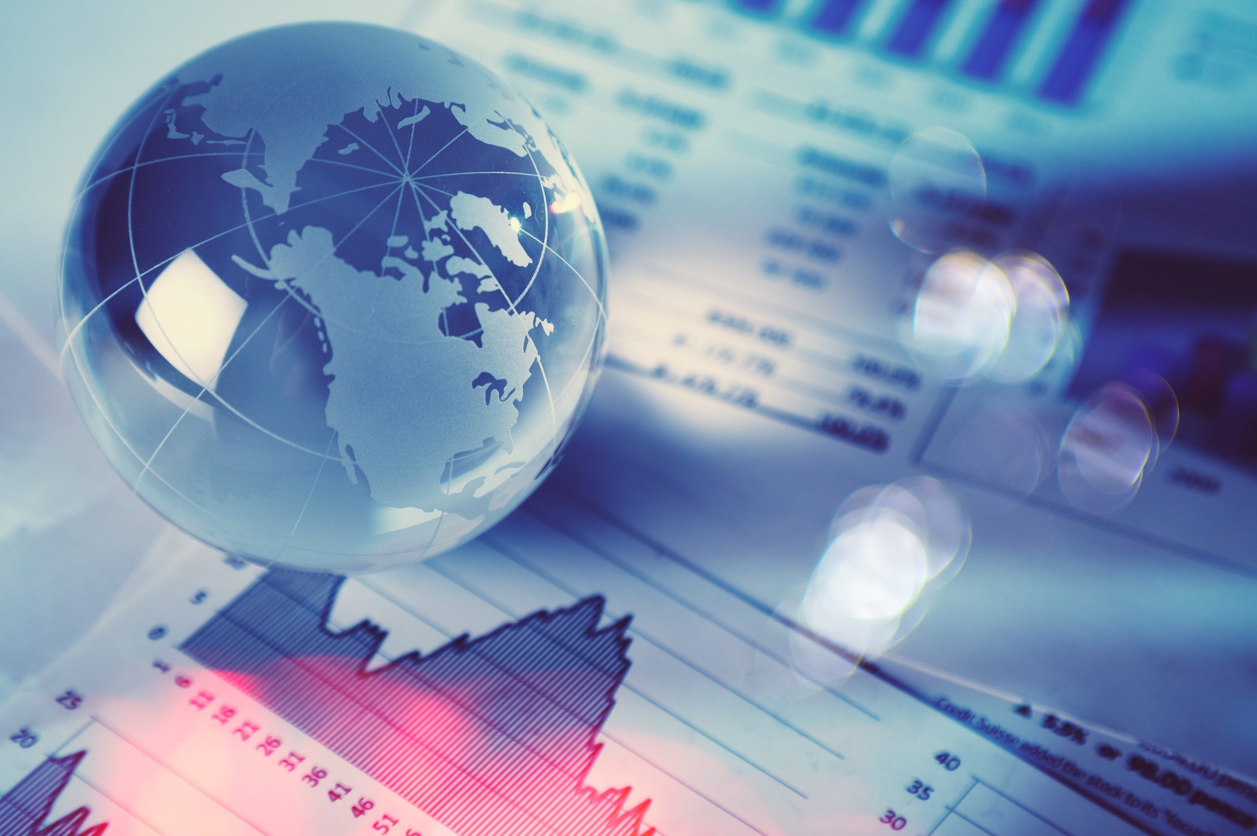 Glass globe with financial reports and graphs